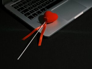 a heart shaped lollipop sitting on top of a laptop computer